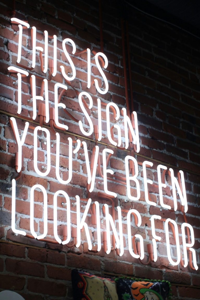 The sign you have been looking for von Austin Chan Neon-Schild auf Backsteinmauer: "This is the Sign you've been looking for"